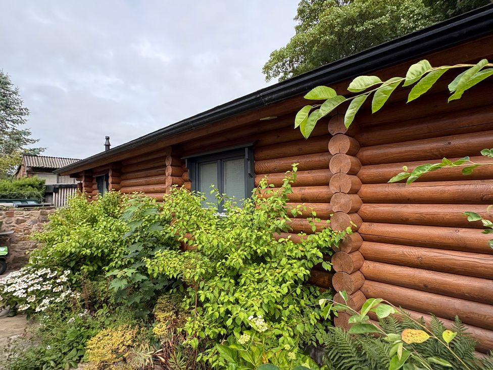 An exterior view of a log cabin surrounded by plants at The Log Cabin in Ormskirk