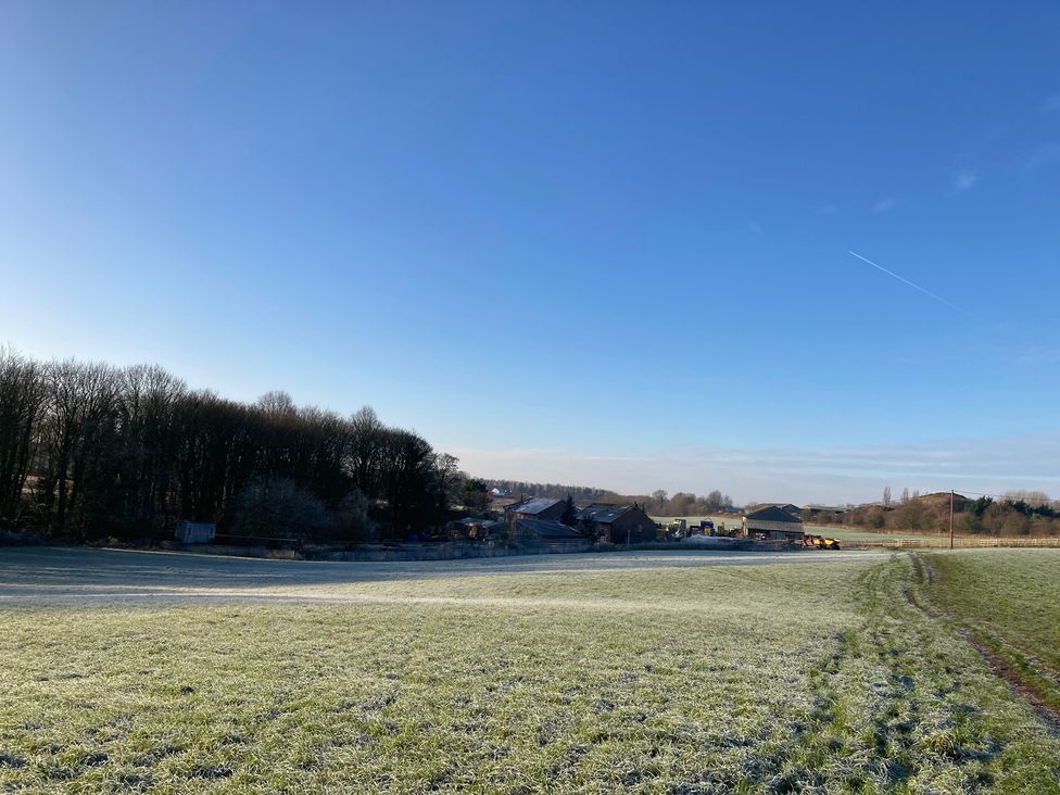 A field with buildings and trees at The Log Cabin in Ormskirk