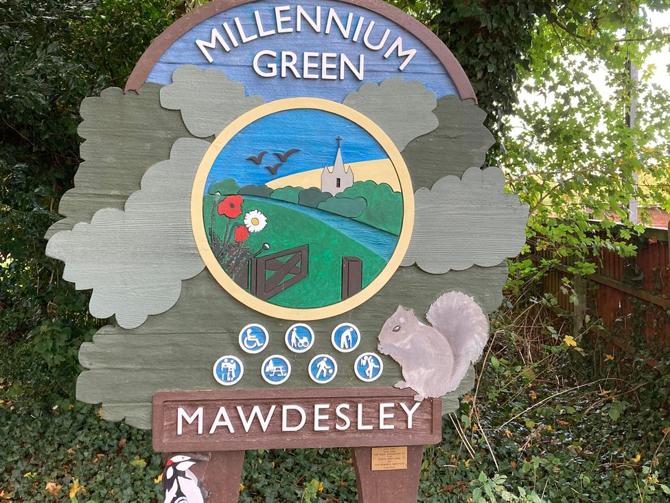 A sign for Millennium Green in Mawdesley with images of a squirrel and nature