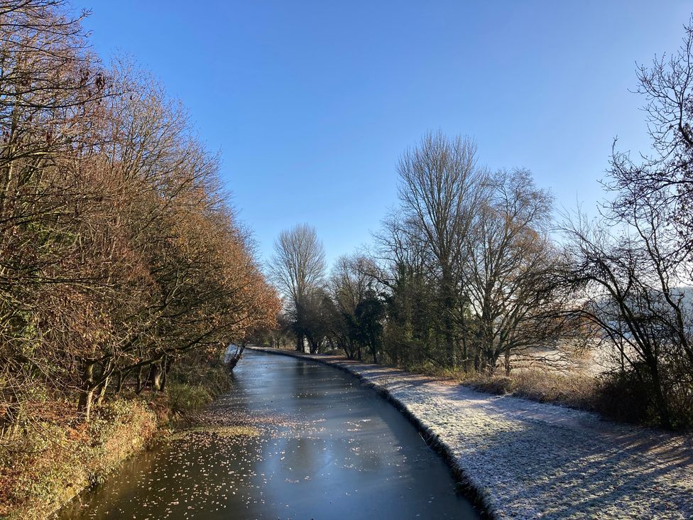 A canal with trees and a pathway at The Log Cabin in Burscough