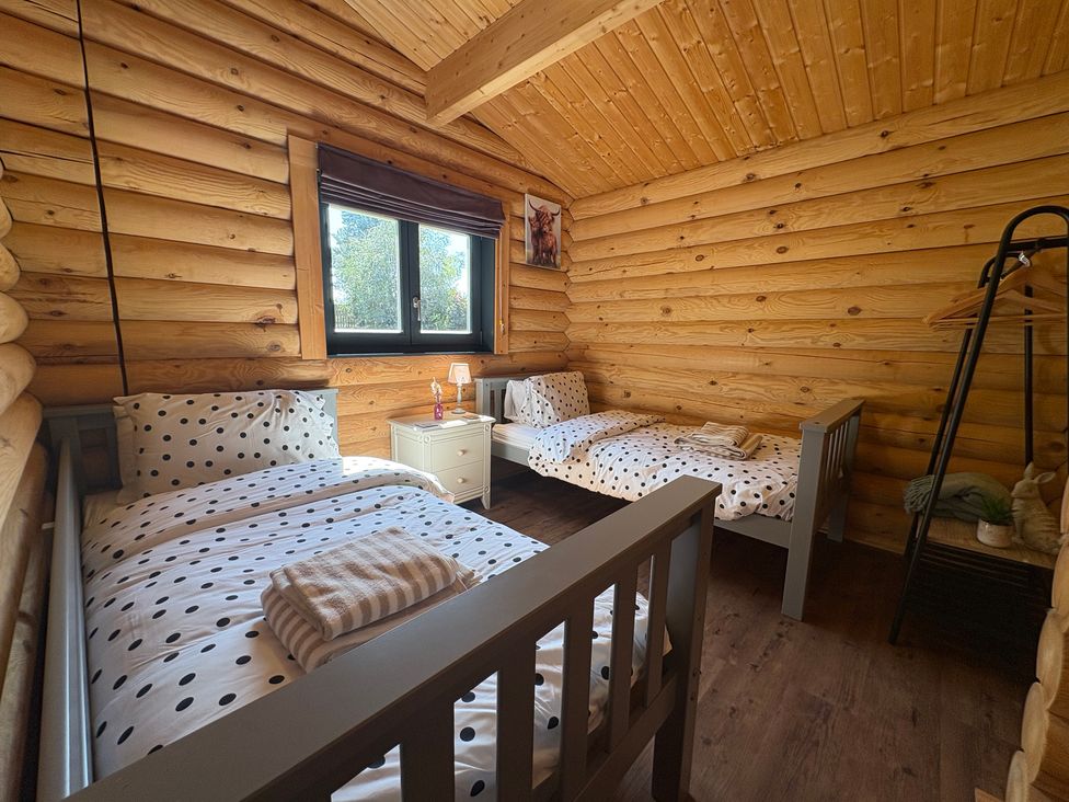A bedroom with two beds and a nightstand at The Log Cabin in Burscough