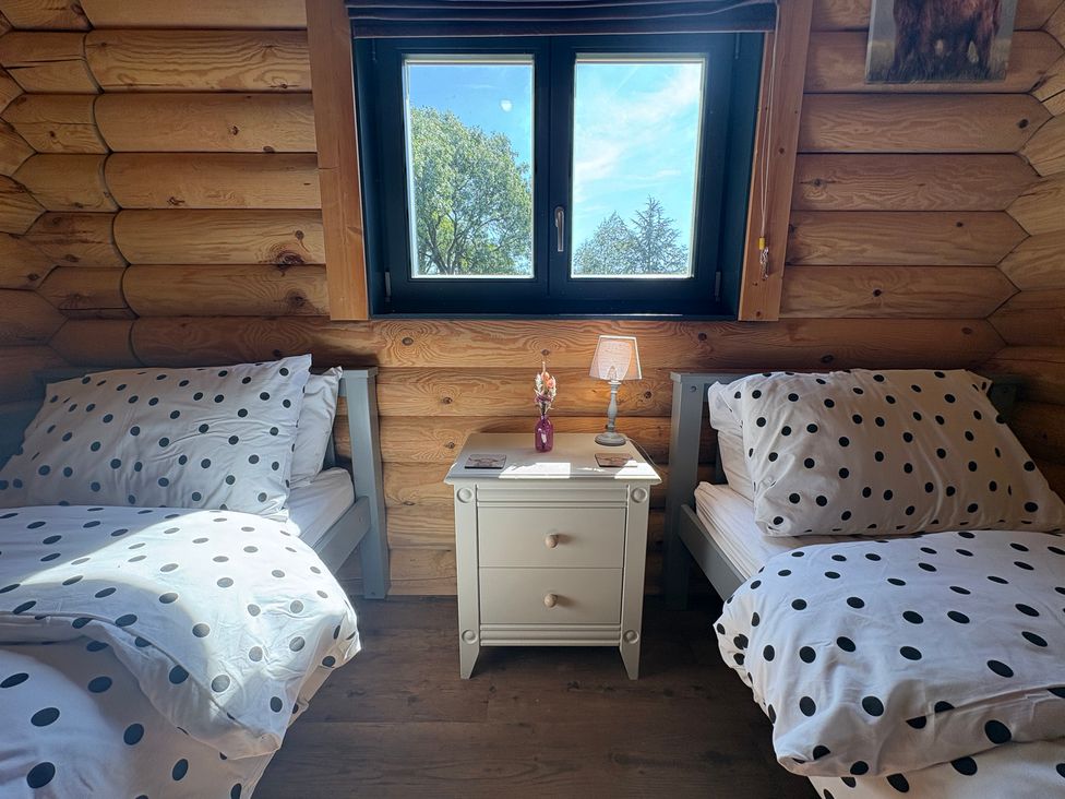 A bedroom with two beds and a window at The Log Cabin in Burscough
