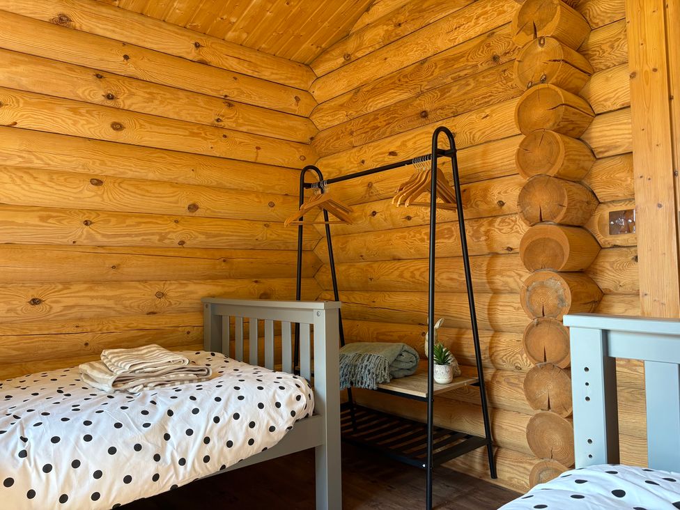 A bedroom with beds and a clothing rack at The Log Cabin in Burscough