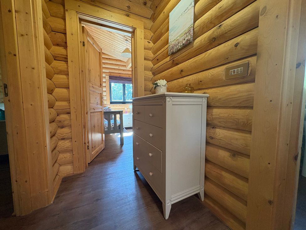 A hallway with a dresser and wooden walls at The Log Cabin in Burscough