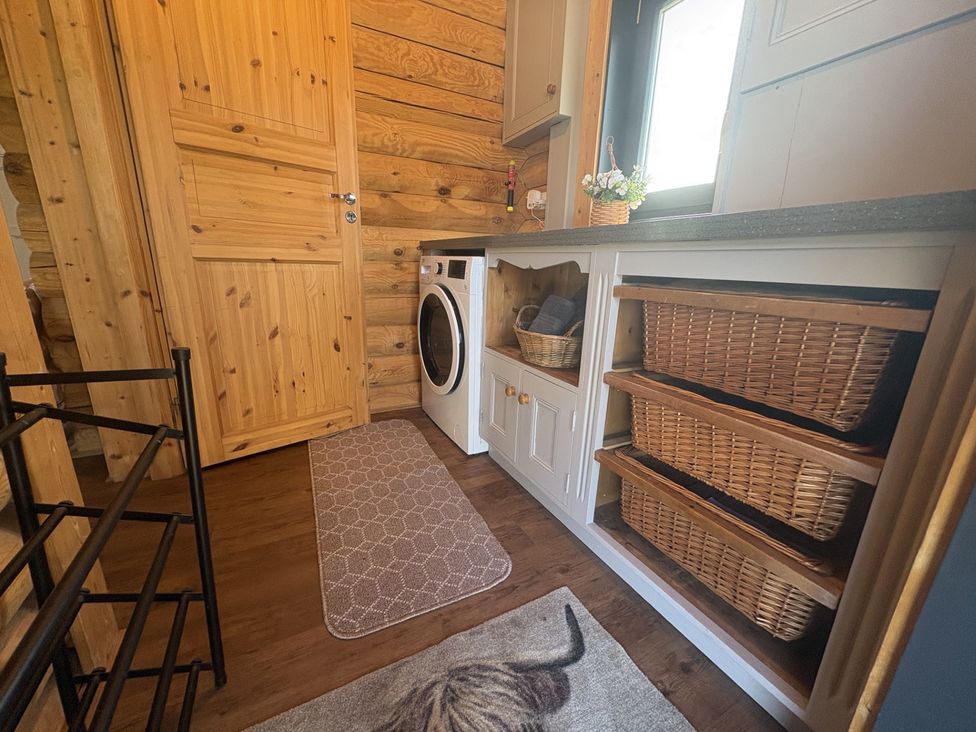 A laundry room with a washing machine and storage baskets at The Log Cabin in Burscough
