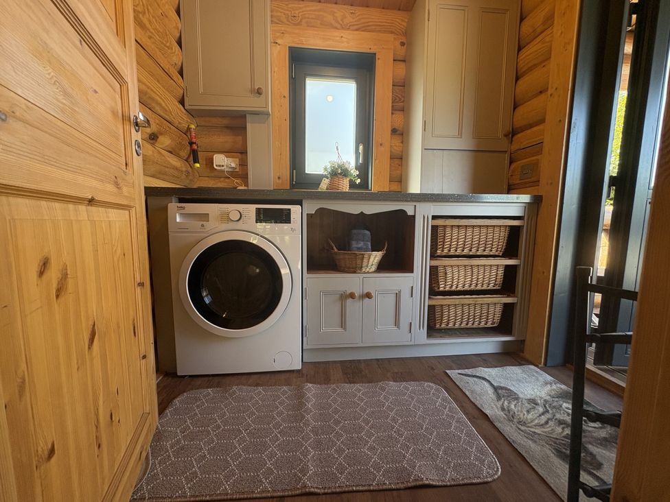 A laundry room with a washing machine and storage baskets at The Log Cabin in Burscough