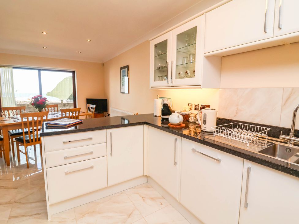 A kitchen with cabinets and dining table at 1 Tideways in Bideford