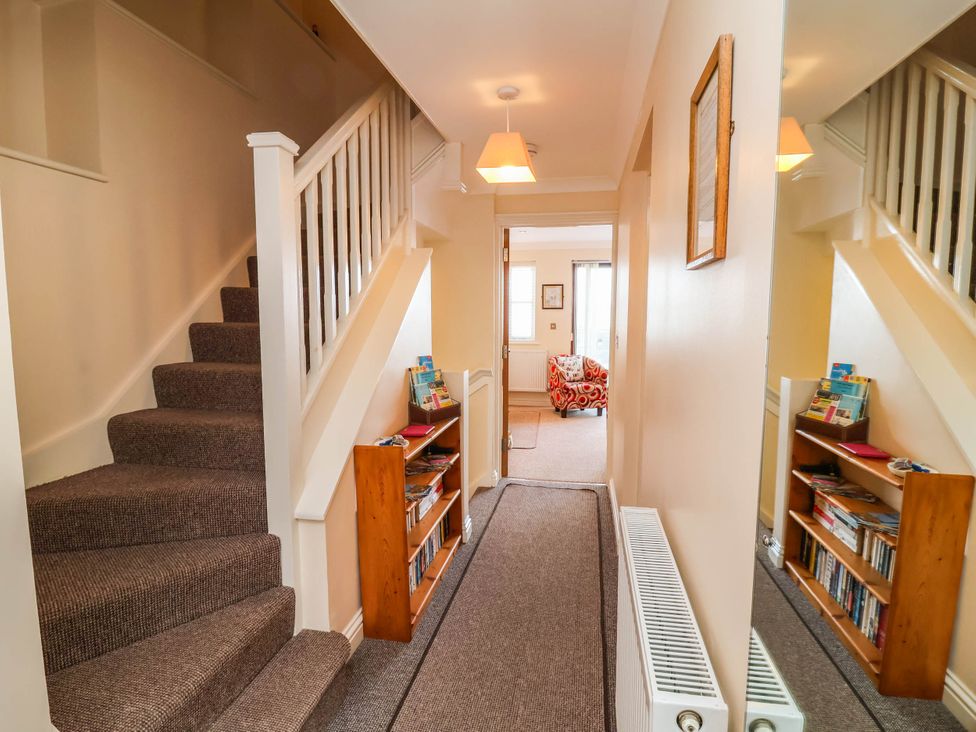 A hallway with a staircase and bookshelf at 1 Tideways Bideford