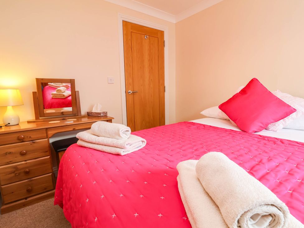 A bedroom with a bed and a dressing table at 1 Tideways in Bideford