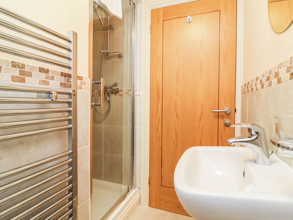 A bathroom with a shower, sink, and towel rail at 1 Tideways Bideford