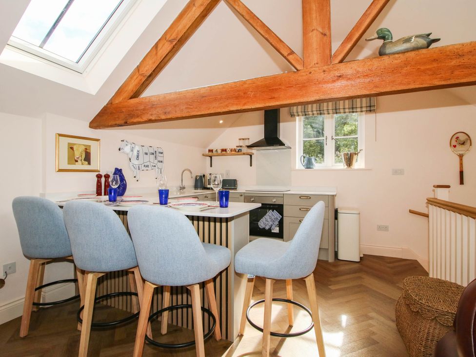 A kitchen with bar stools and a window at Little Red Barn in Wallop near Westbury