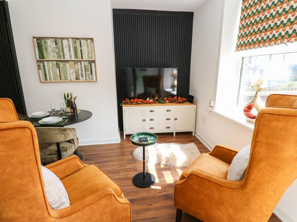 A living room with armchairs and a TV at Brodie Cottage in Brighouse