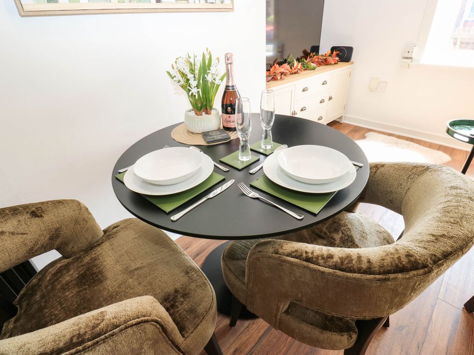 A dining table set with plates and champagne at Brodie Cottage in Brighouse