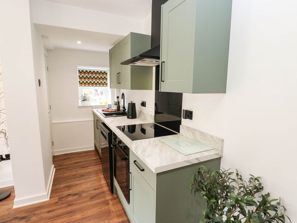 A kitchen with cabinets, countertop, sink, and cooktop at Brodie Cottage Brighouse