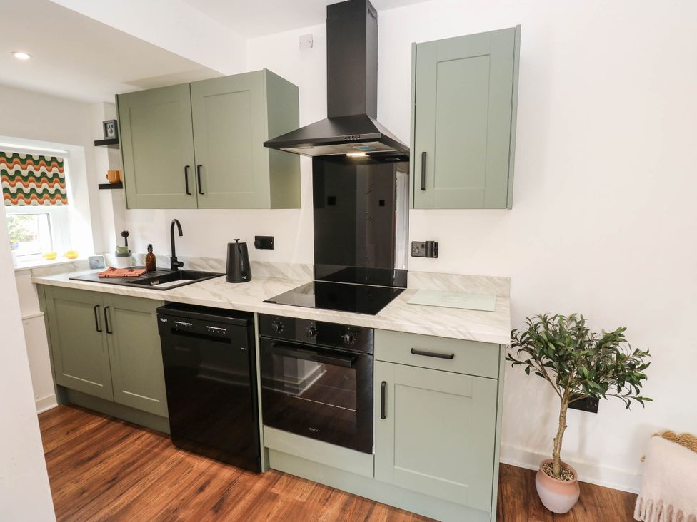 A kitchen with green cabinets and a stove at Brodie Cottage in Brighouse