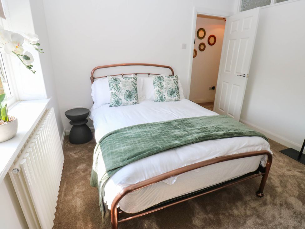 A bedroom with a bed and plant at Brodie Cottage in Brighouse