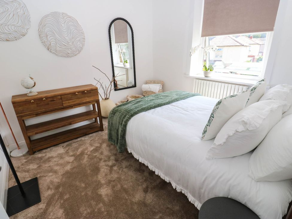 A bedroom with a bed and mirror at Brodie Cottage in Brighouse