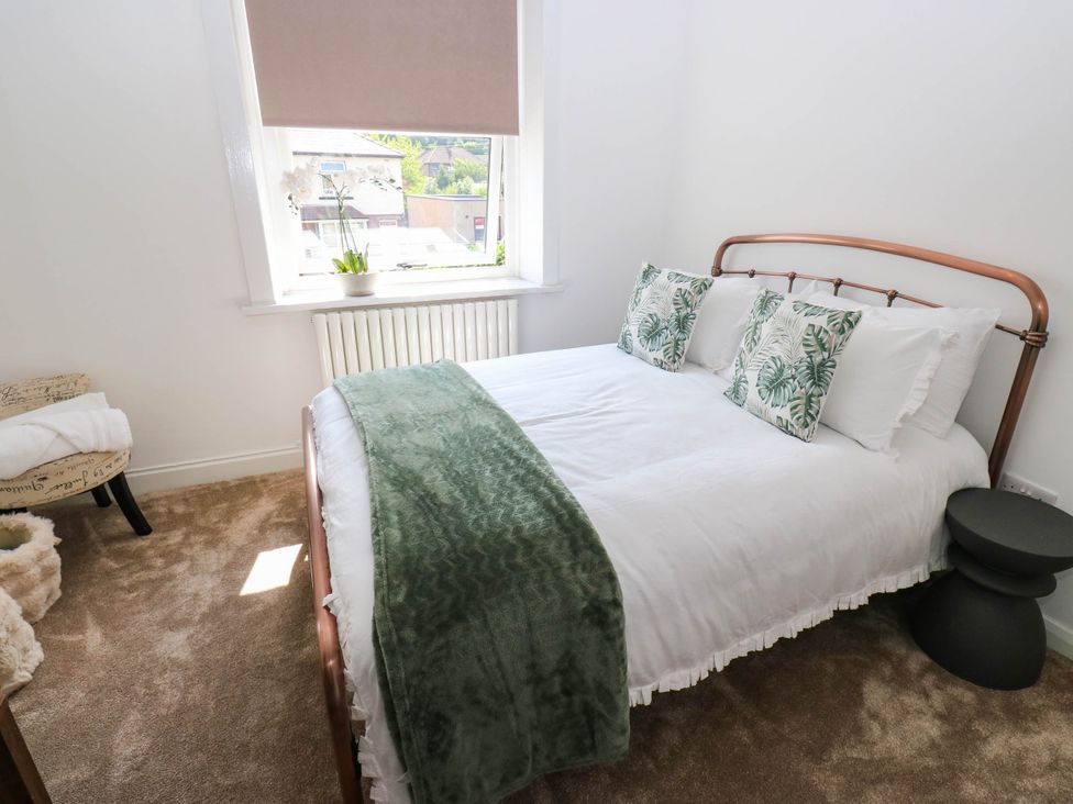 A bedroom with a bed and chair at Brodie Cottage in Brighouse
