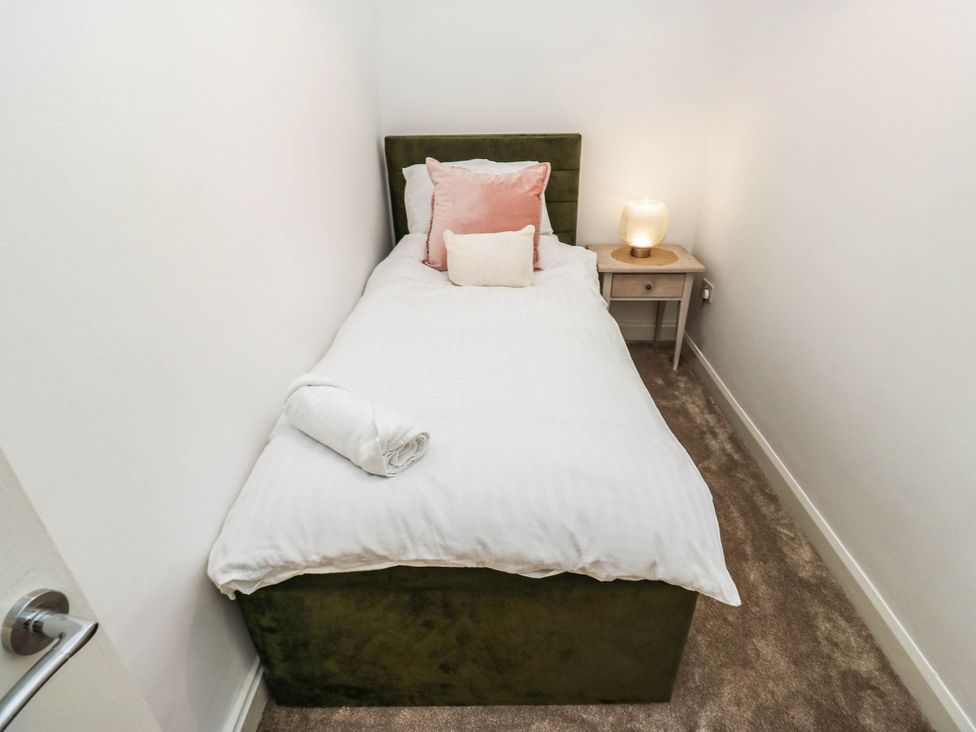 A bedroom with a single bed and bedside table at Brodie Cottage in Brighouse