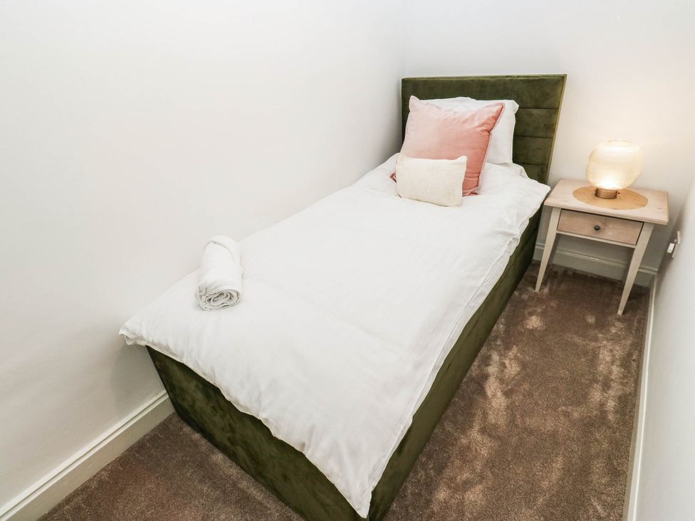 A bedroom with a bed and bedside table at Brodie Cottage in Brighouse