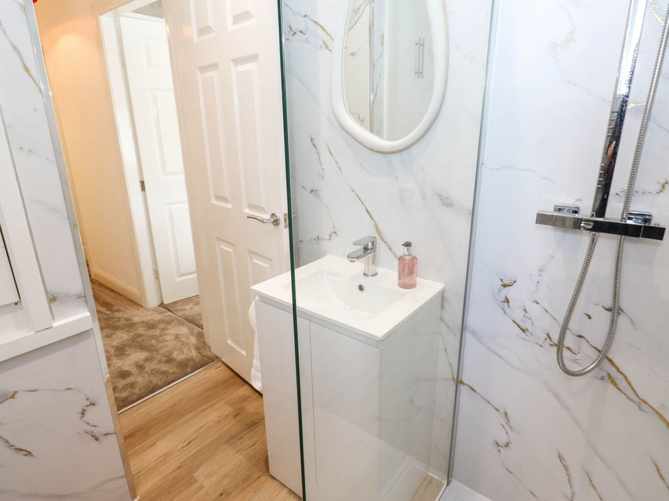 A bathroom with sink shower and mirror at Brodie Cottage in Brighouse