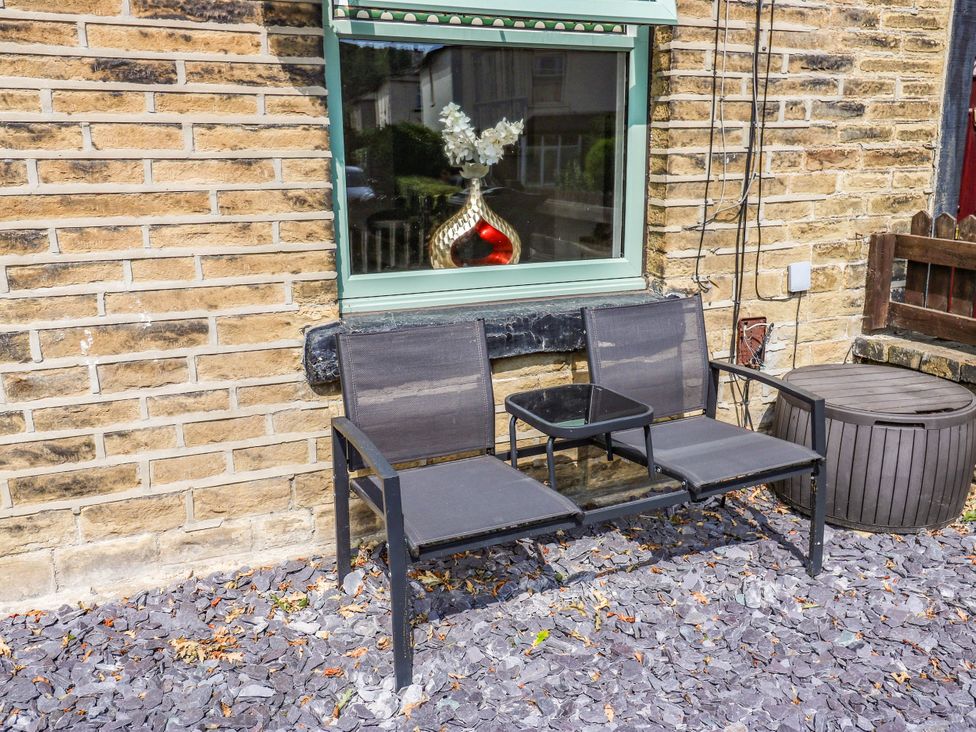 A seating area with chairs and a table by a window at Brodie Cottage in Brighouse
