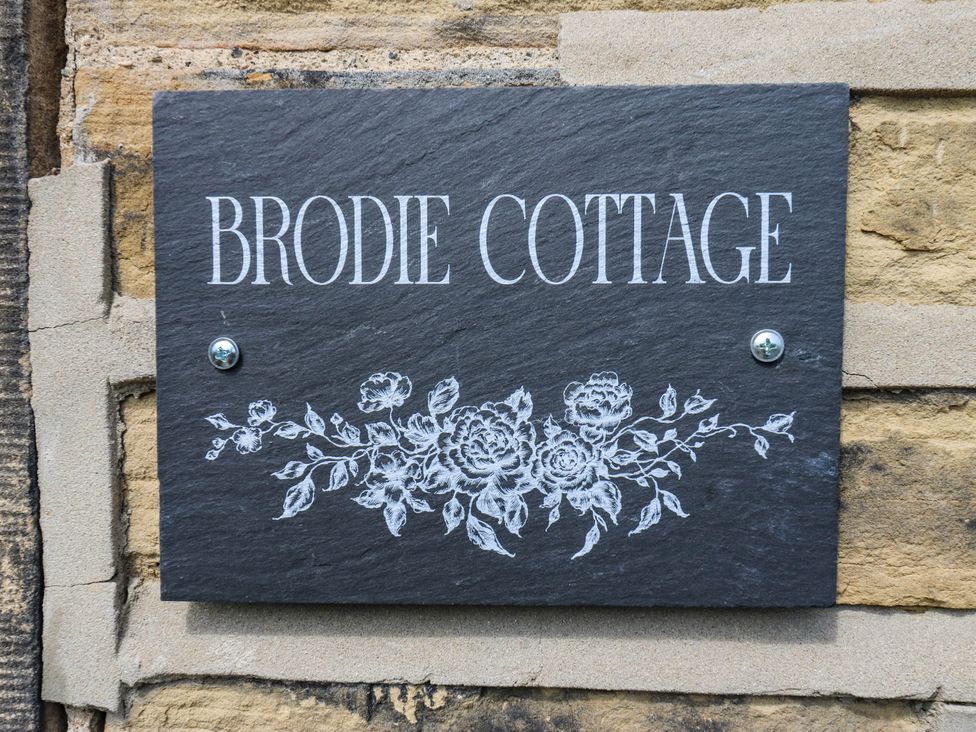 A sign for Brodie Cottage with floral design at Brodie Cottage in Brighouse
