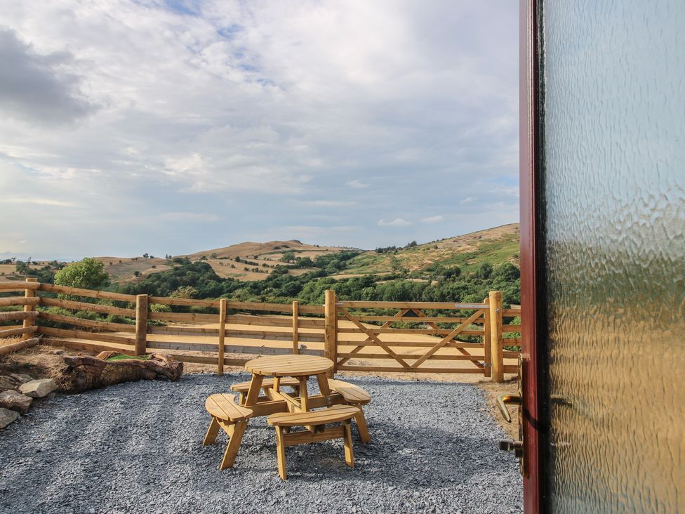 An outdoor area with a table and chairs overlooking a landscape at Darn Mawr 