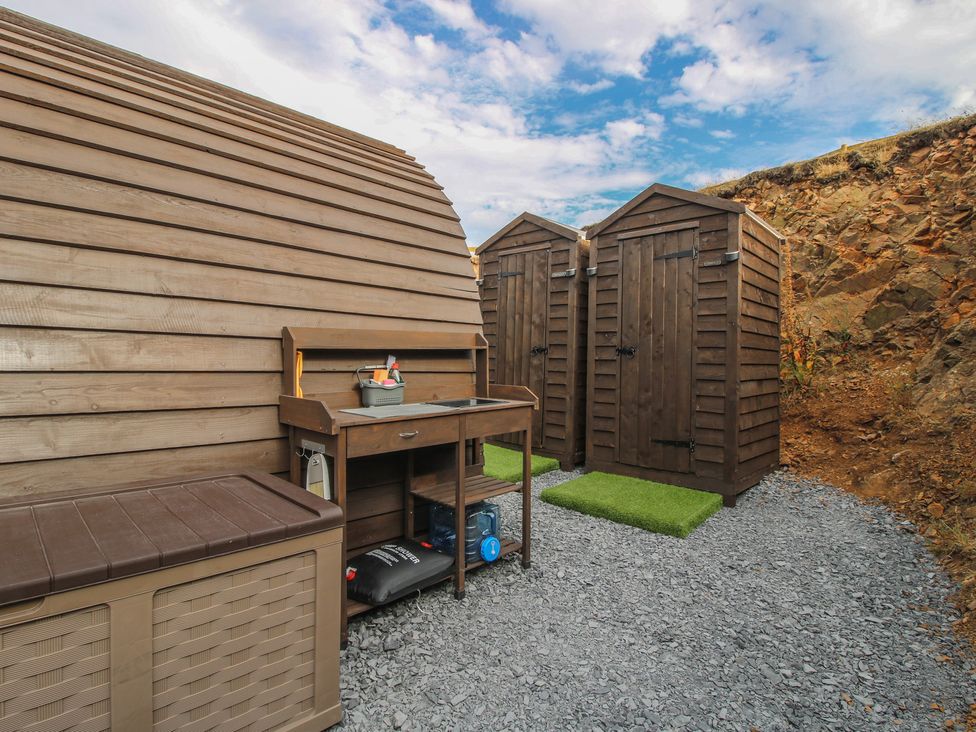 An outdoor area with storage sheds, a bench, and a gravel surface at Darn Mawr 
