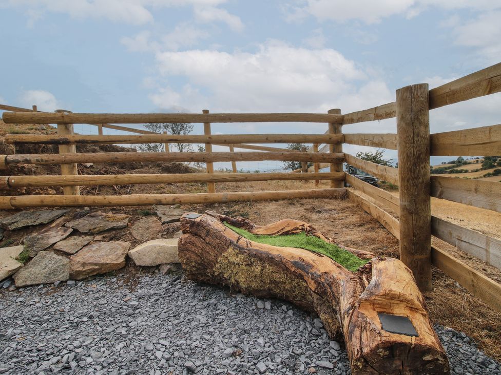 An outdoor area with a wooden fence and a log at Darn Mawr 