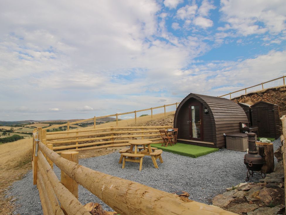 An outdoor area with a wooden cabin and seating at Darn Mawr 