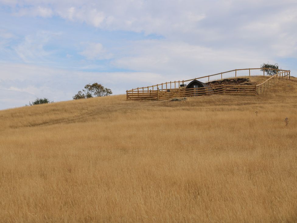 A hill with a fenced structure and grassland at Darn Mawr 