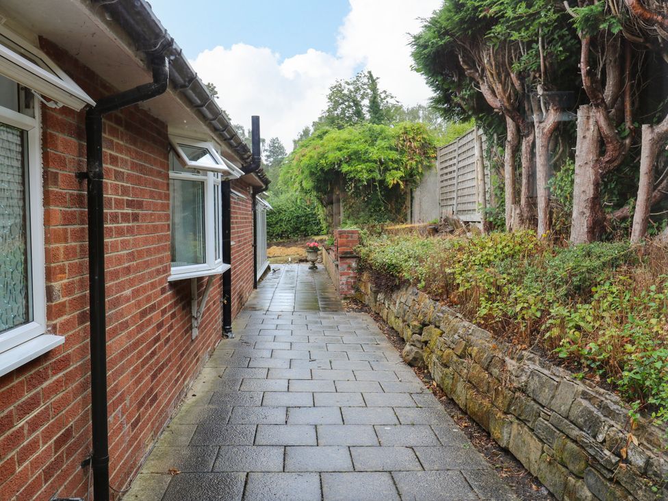 A pathway alongside a brick wall with windows at 12 The Dell Bardsey near Wetherby