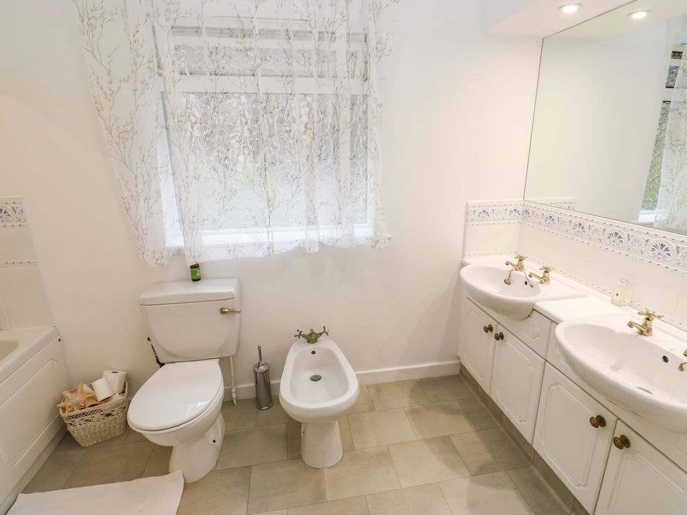 A bathroom with a toilet, bidet, two sinks and a window at 12 The Dell in Bardsey near Wetherby