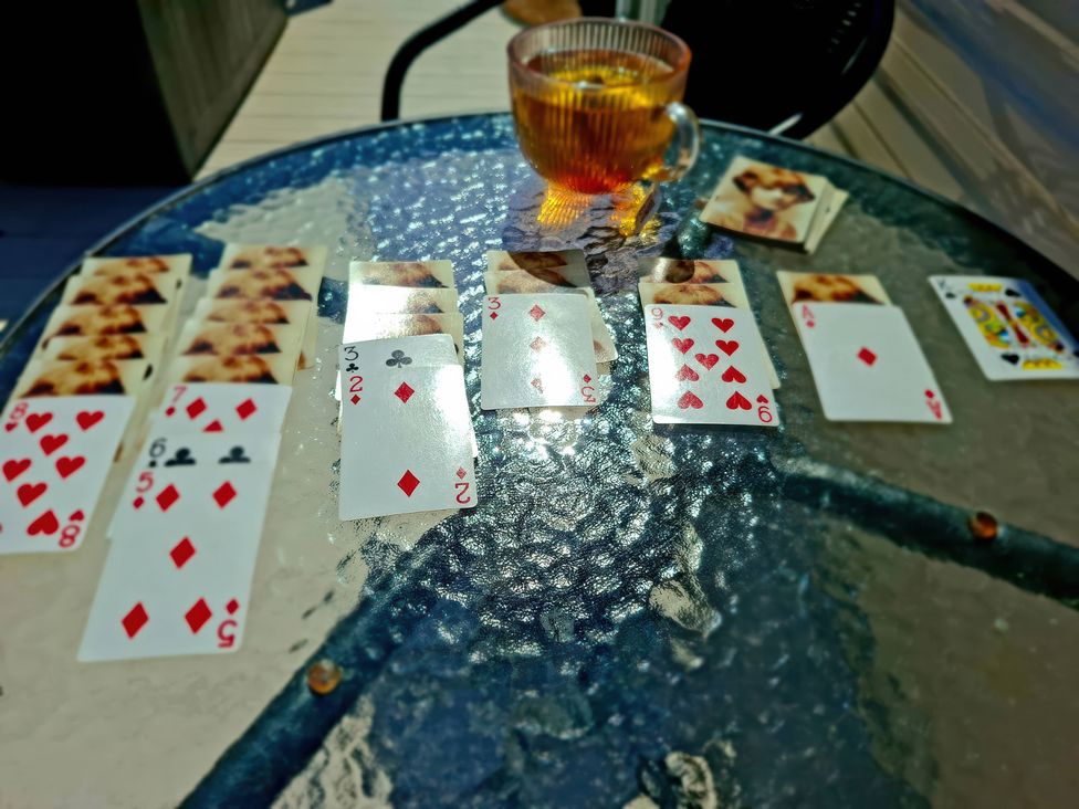 Playing cards laid out on a glass table with a cup of tea at Demelza (B34) Seven Bays Holiday Park Padstow
