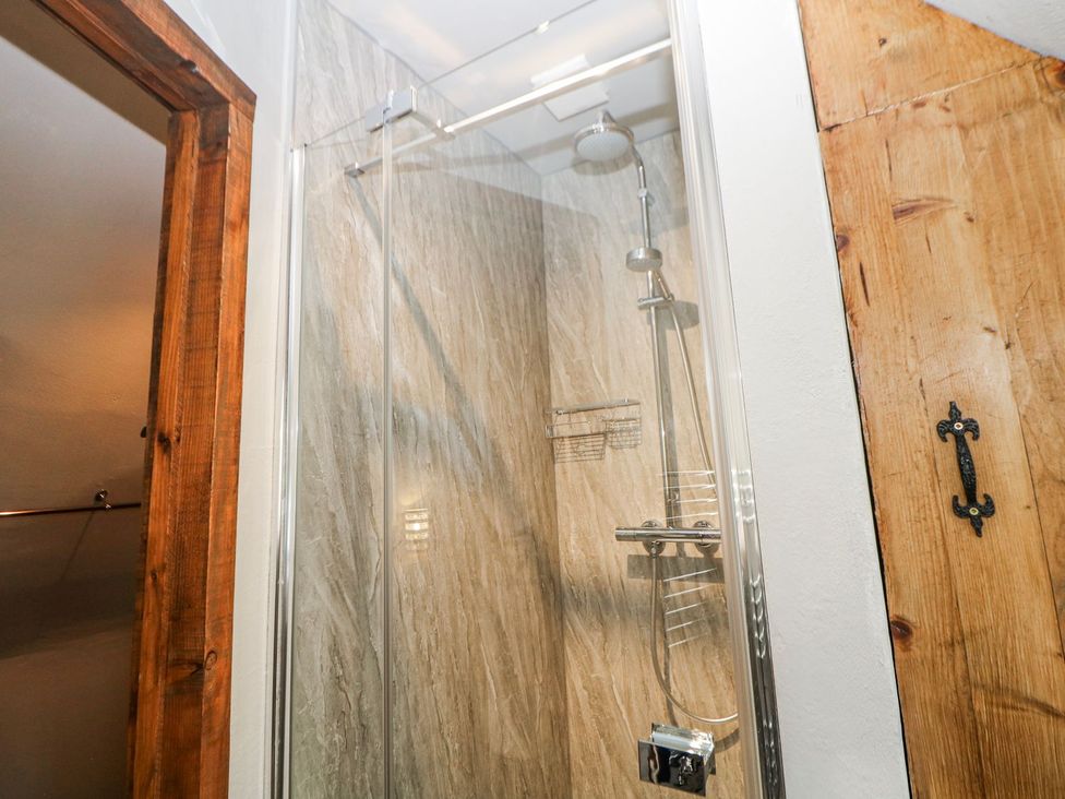 A shower with glass doors and tiled walls at Little Mill in Ashover