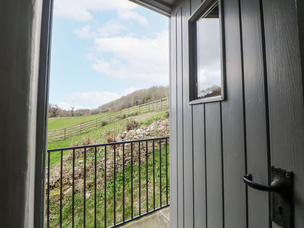 A view from an open door looking onto a grassy field with a fence at Little Mill Ashover