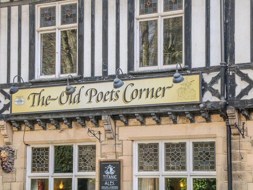 The Old Poets Corner sign on a building with windows in Ashover