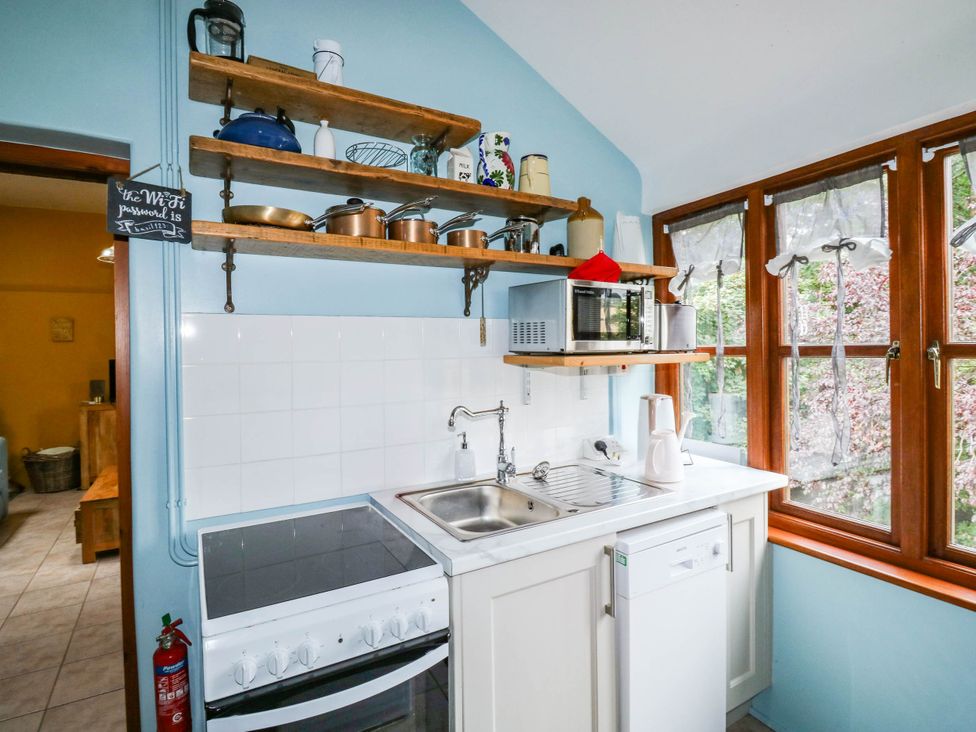 A kitchen with a stove, sink, microwave and shelves at The Old Forge in Kingsbridge