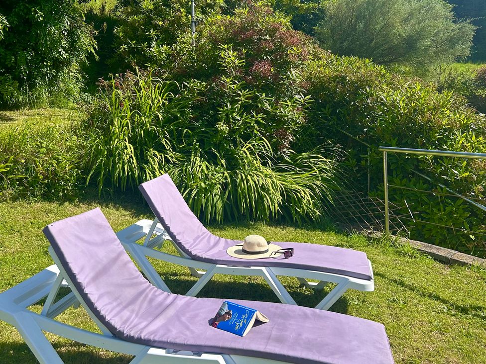 Two lounge chairs with a hat and book in a garden at The Old Forge Bickerton near East Prawle
