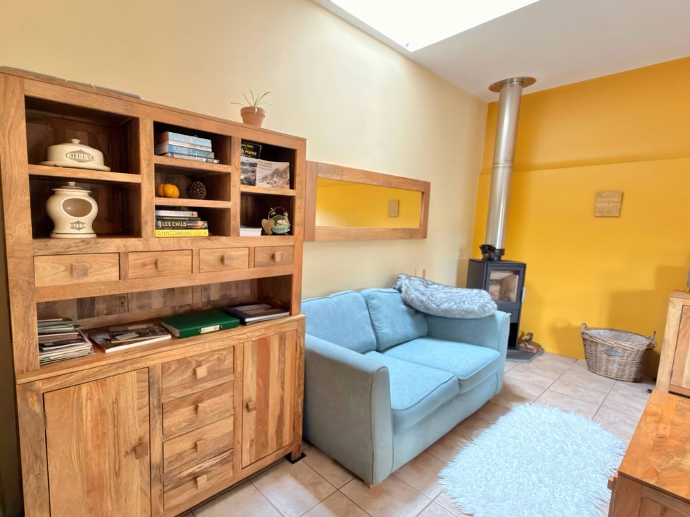 A living room with a sofa and bookshelf at The Old Forge in Hallsands