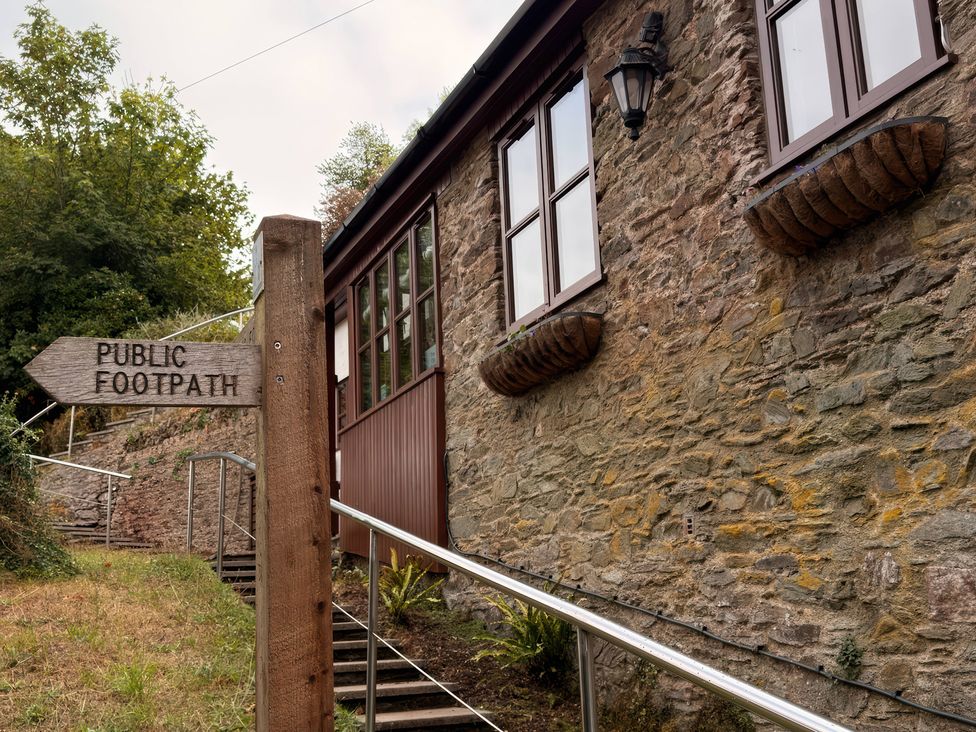 A public footpath sign next to a stone building at The Old Forge in Hallsands