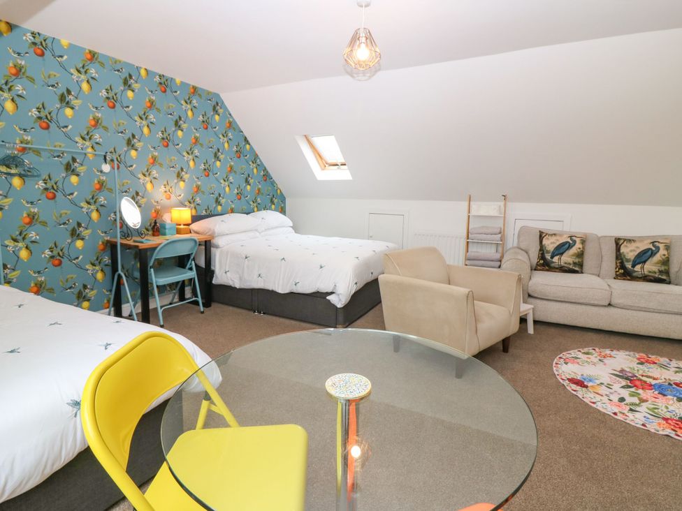 A bedroom with two beds and seating area at Hill View Studio in Hawick