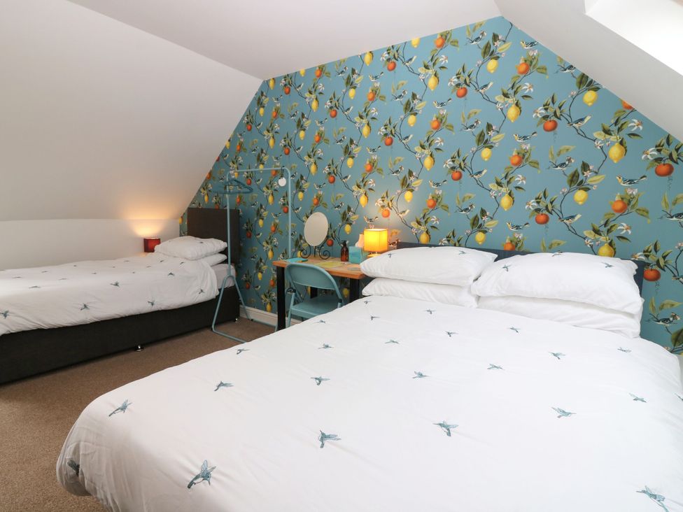 A bedroom with two beds and decorative wallpaper at Hill View Studio in Hawick