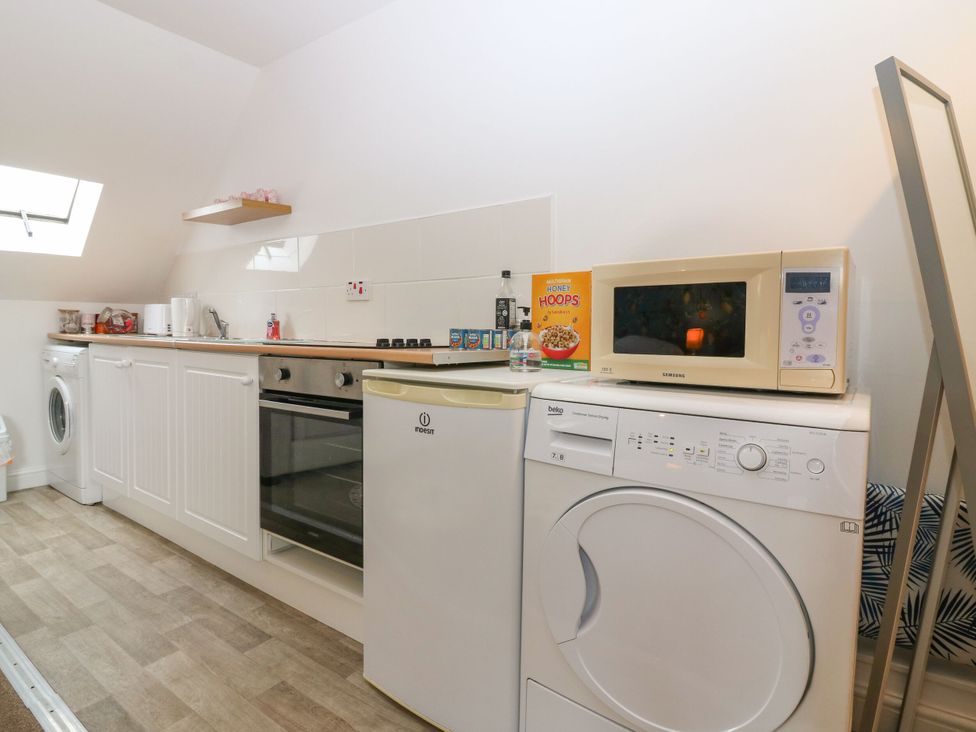 A kitchen with a washing machine and microwave at Hill View Studio in Hawick
