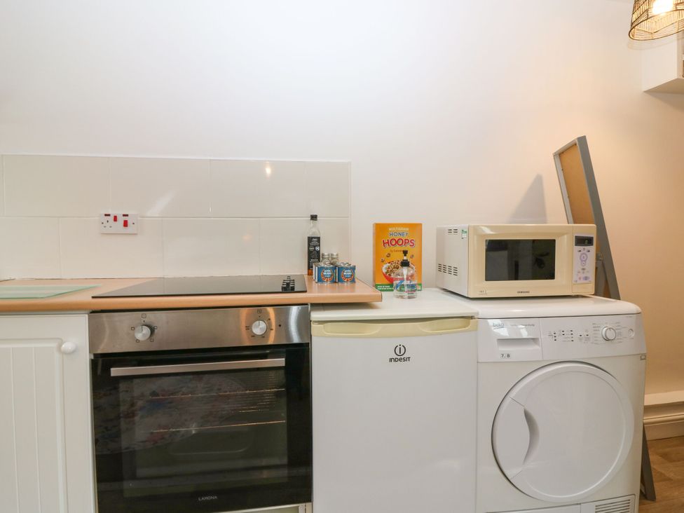 A kitchen with an oven, hob, microwave, and washing machine at Hill View Studio in Hawick