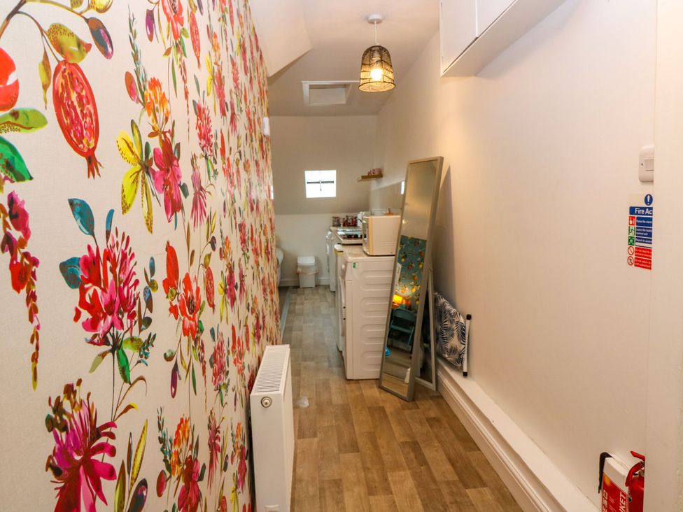 A bathroom with floral wallpaper and a washing machine at Hill View Studio in Hawick