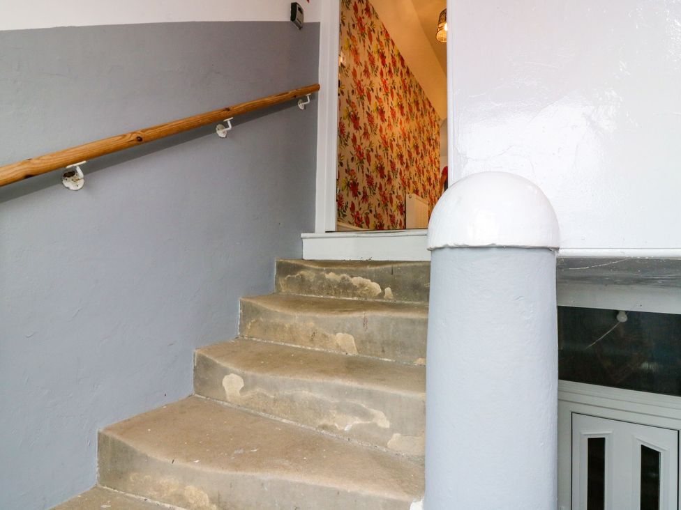 A staircase with a handrail and wall leading to a door at Hill View Studio in Hawick