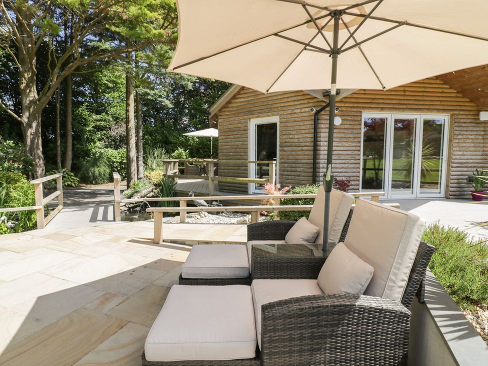 An outdoor seating area with chairs and an umbrella at Brambleside Lodge in Truro