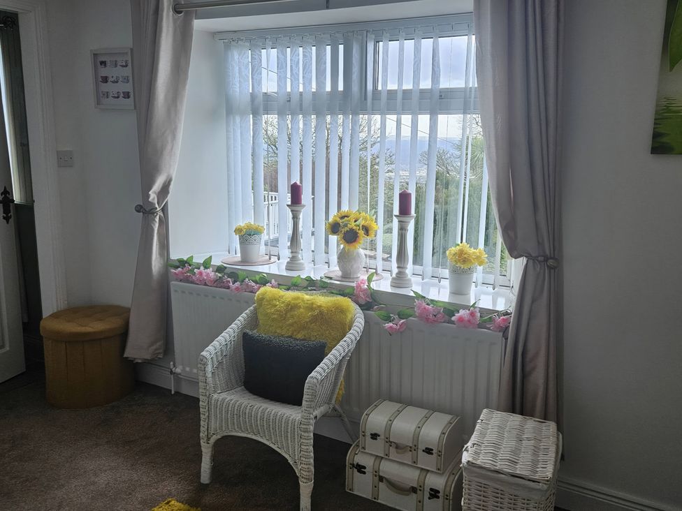 A living room with a window displaying flowers and candles at Mourne Mountains View in Dunmurry